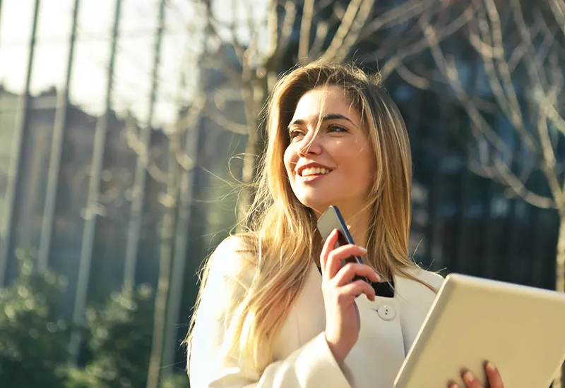 Eine blonde Frau mit Laptop und Smartphone